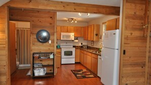 A compact kitchen with wooden cabinets, a microwave, a stove, and a refrigerator.