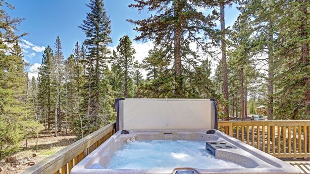 A hot tub on a wooden deck surrounded by a forest.