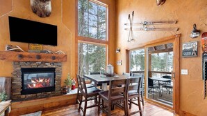 Ein gemütliches Interieur mit Kamin aus Stein, einem Holztisch und Stühlen.