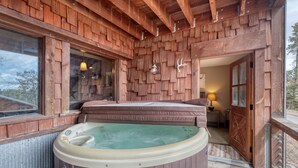 Eine Holzhütte mit Whirlpool, einem Bett und einem kleinen Tisch mit einer Lampe.