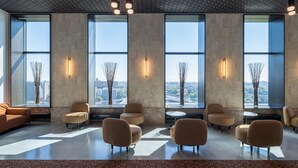Una sala lounge moderna con ampie finestre, diverse zone relax e vasi decorativi.