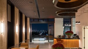 Una moderna hall d'albergo con area bar, posti a sedere e vista sulla città.