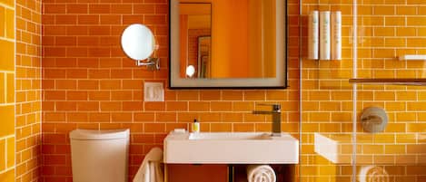 Un baño con inodoro, lavabo y espejo. Hay toallas y artículos de aseo en el lavabo.
