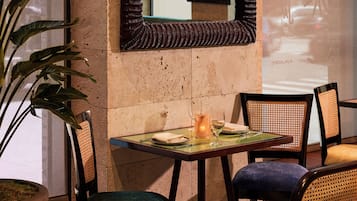 A dining area with a table, chairs, and a large mirror on the wall.