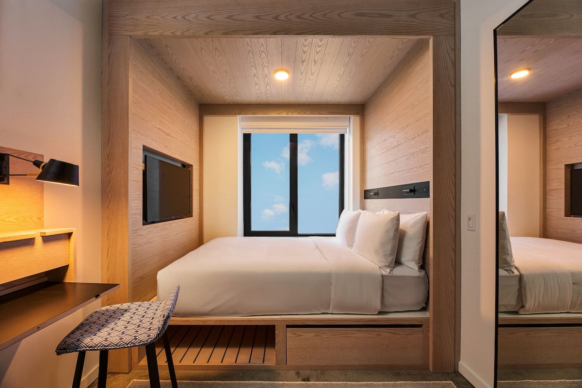 A compact bedroom with a bed, a desk, and a chair.