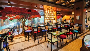 Un ristorante con pavimenti in legno, diversi tavoli e sedie, e un'ampia pianta artificiale.