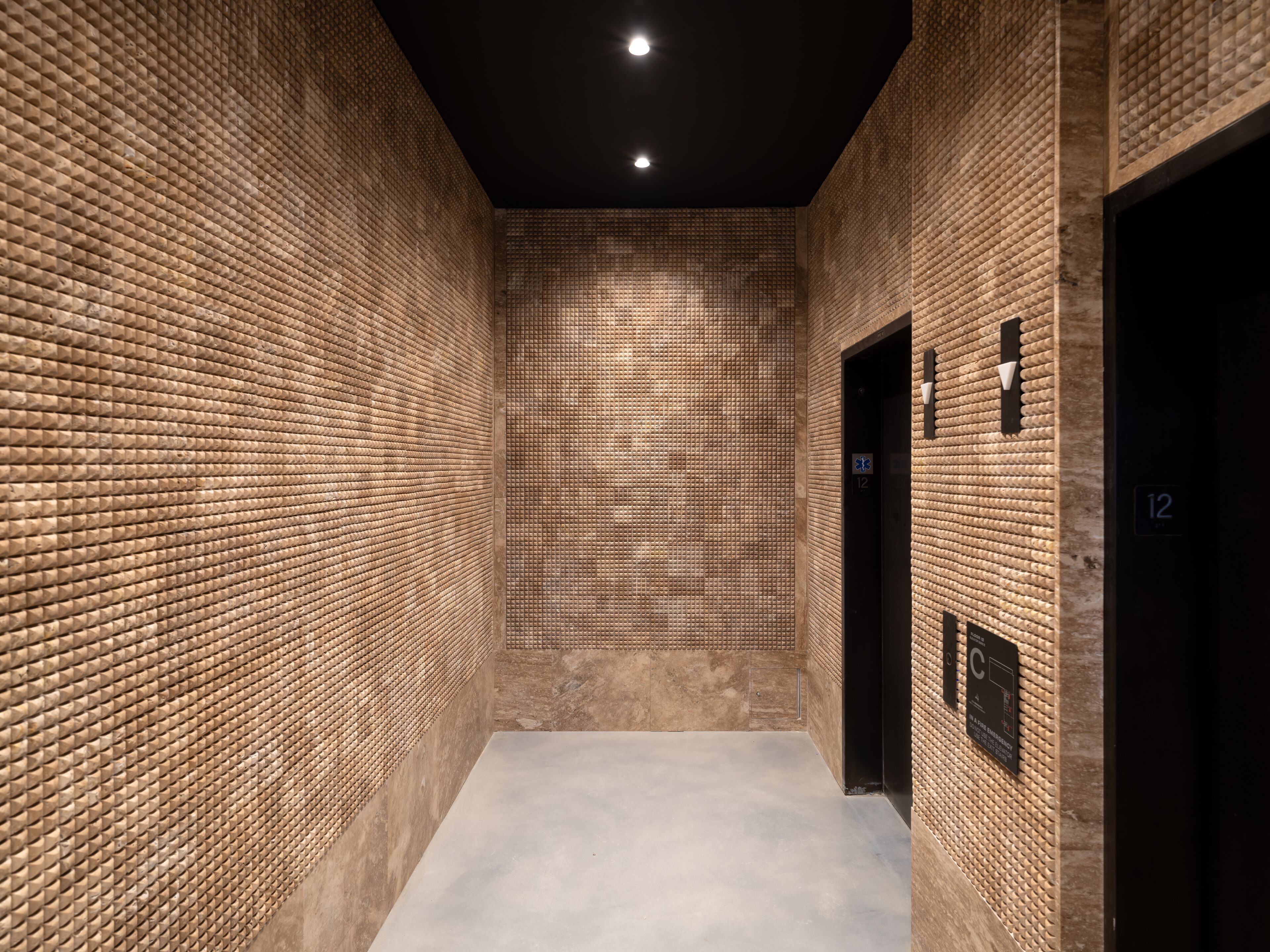 A corridor with textured brick walls and a recessed ceiling.