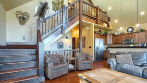 A spacious living area with a wooden staircase, leather sofas, and a dining table. - Foote Creek Lodge (Lead)