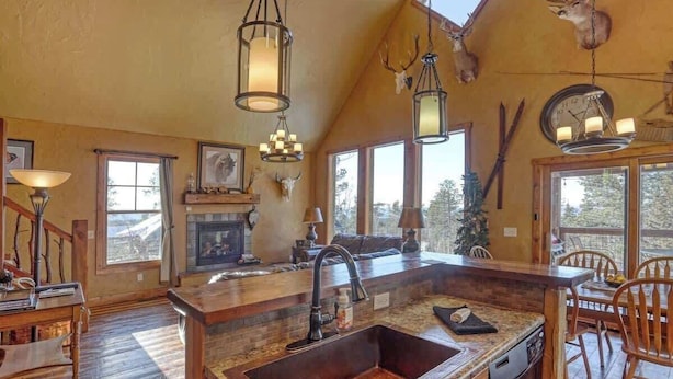 A rustic kitchen with a large island, wooden flooring, and a fireplace. - Big Pine Lodge – Rustic charm, hot tub, pet friendly, and room for 12 near Terry Peak! (Lead)