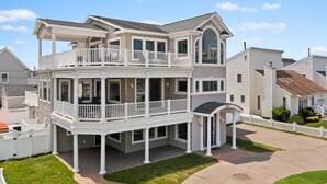 A two-story house with a balcony, a covered porch, and a garage. - 5BR w/ Pool, Hot Tub, Cabana, Elevator & Game Rm (Brigantine)