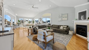 A spacious living room with a large sofa, a wooden chair, and a fireplace. - 5BR w/ Pool, Hot Tub, Cabana, Elevator & Game Rm (Brigantine)