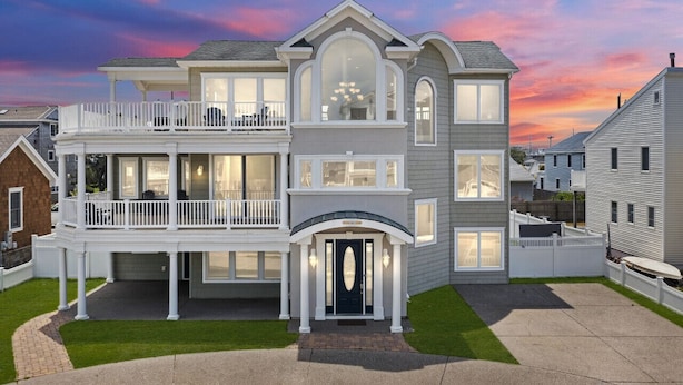A large, two-story house with a balcony, a covered front porch, and a well-maintained lawn. - 5BR w/ Pool, Hot Tub, Cabana, Elevator & Game Rm (Brigantine)