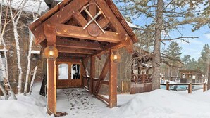 A rustic wooden cabin with a snow-covered entrance and a small porch area. - Alpine Escape (Lead)