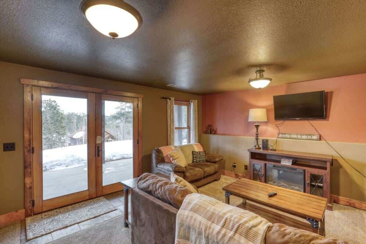 A cozy living room with a brown leather sofa, a wooden coffee table, and a television mounted on the wall.