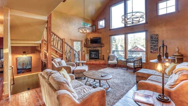 A spacious living room with a fireplace, comfortable seating, and large windows. - Gunstock Lodge (Lead)