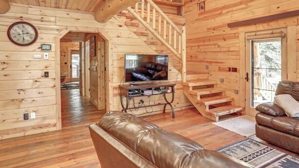 A wooden cabin interior with a living room, a staircase, a television, and a leather sofa. - Eagle`s Lair (Lead)
