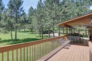 A wooden deck with outdoor furniture, surrounded by a forested area. - Chase`s cabin by the creek (Lead)