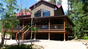 A two-story wooden cabin with a balcony, surrounded by trees. - Triple R Retreat – Hot Tub, Loft & Black Hills Views (Lead)