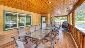 Un espace extérieur abrité, doté d’une longue table et de chaises, de murs en bois et de grandes fenêtres.