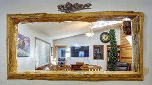 Un salon avec un miroir à cadre en bois, une télévision, une horloge et un sapin de Noël.