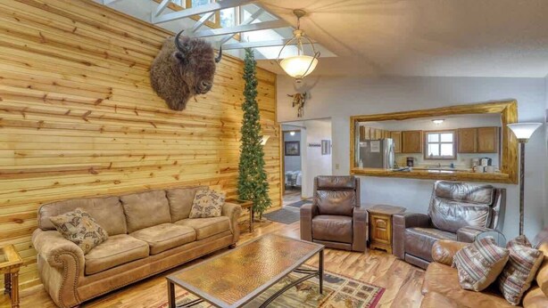 Un salon chaleureux avec un mur en bois, un canapé, une table basse et des fauteuils en cuir.