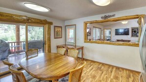 Une table à manger en bois avec des chaises, un grand miroir et un téléviseur fixé au mur.