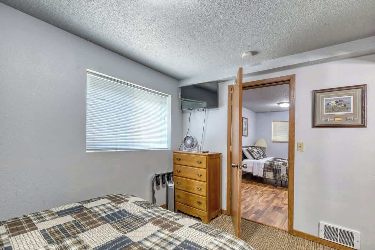 A bedroom with a bed, a dresser, a radiator, and a door leading to another room.