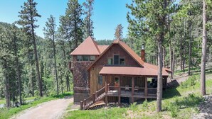 Un chalet rustique avec une façade en pierre, une terrasse en bois et un chemin de terre qui y mène.