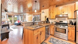 Una cocina amplia con armarios de madera, encimera de granito y electrodomésticos de acero inoxidable, además de un comedor con mesa y sillas.