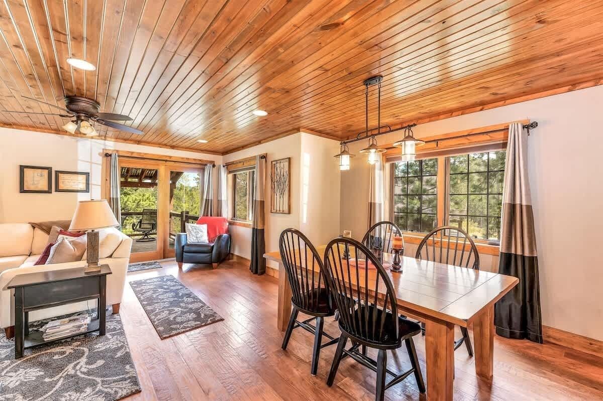 Amplia sala de estar con techo de madera, una mesa de comedor con sillas, un sofá y una mesa de centro.