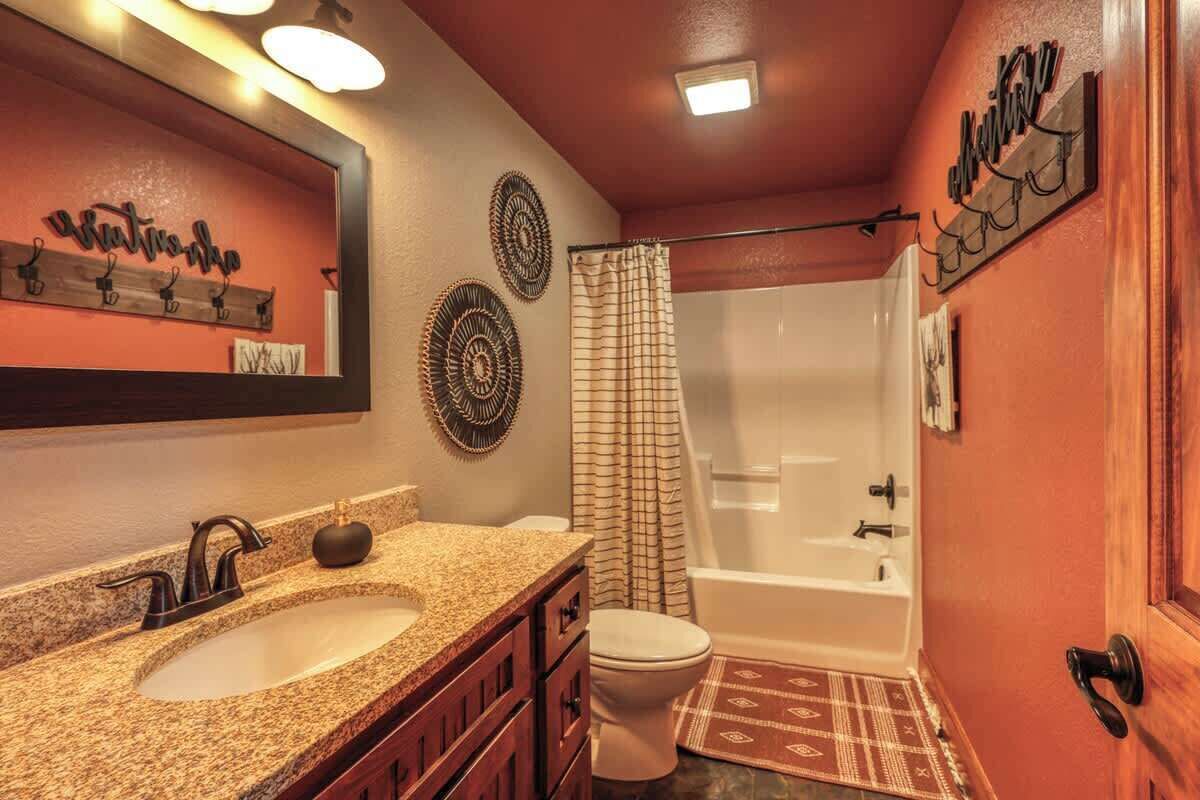 A bathroom with a double sink vanity, a toilet, a bathtub, and a shower curtain.
