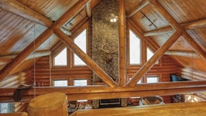 A log cabin interior with a stone fireplace, wooden beams, and a high ceiling. - Bear Butte Gulch Lodge - Private cabin with gorgeo (Deadwood)
