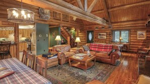 A log cabin interior with a dining area, living room with a sofa and coffee table, and a kitchen in the background. - Bear Butte Gulch Lodge - Private cabin with gorgeo (Deadwood)