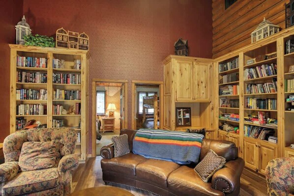 Un salon chaleureux avec un canapé en cuir, des fauteuils à motifs et des étagères en bois remplies de livres.