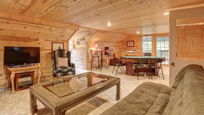 A cozy log cabin interior with a television, sofa, and pool table. - Mountain Oasis - private hot tub and game room. (Lead)