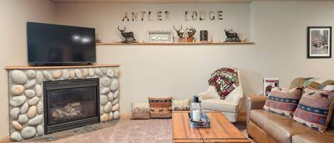 A living room with a stone fireplace, a television, a sofa, and a coffee table.