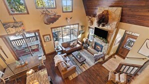 Un salon spacieux avec une cheminée, des murs en bois et des têtes d’animaux fixées au mur.