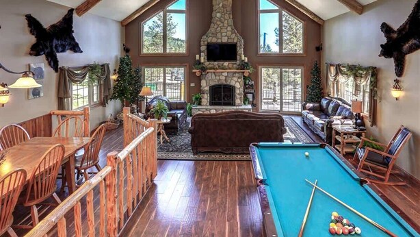 A spacious living area with a pool table, wooden furniture, and a stone fireplace. - Rocky Ridge Lodge – A Black Hills Escape for Family & Friends! (Lead)
