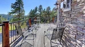 A wooden deck with metal chairs and a table, overlooking a forested area. - Rocky Ridge Lodge – A Black Hills Escape for Family & Friends! (Lead)