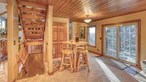 A wooden staircase leading to a dining area with a table and stools. - Rocky Ridge Lodge – A Black Hills Escape for Family & Friends! (Lead)