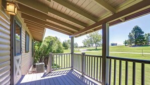 A wooden deck with a railing, overlooking a well-maintained lawn and trees. - Whispering Grace Retreat (Rapid City)