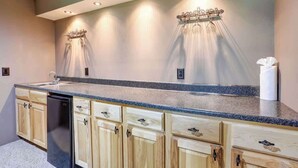 A kitchen with a granite countertop, wooden cabinets, a dishwasher, and a wall-mounted light fixture. - Whispering Grace Retreat (Rapid City)