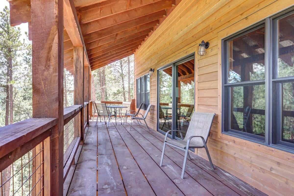 A wooden deck with a covered area, large windows, and outdoor seating.