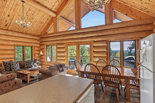 A log cabin interior with a dining area, kitchen, and seating space.