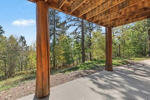 A covered wooden structure with a concrete pathway leading through a forested area.