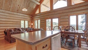 A log cabin interior with a kitchen area, dining table, and seating. - Dakota Log Cabin – Rustic charm, amazing views, wildlife watching & cozy family spaces! (Lead)