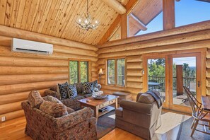 A log cabin interior with a sofa, armchair, and dining table.