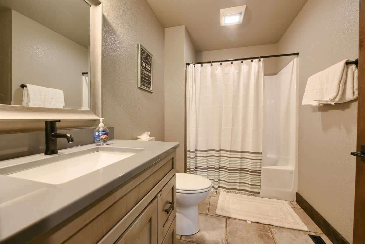 Een badkamer met een wastafel, toilet en douchegordijn.