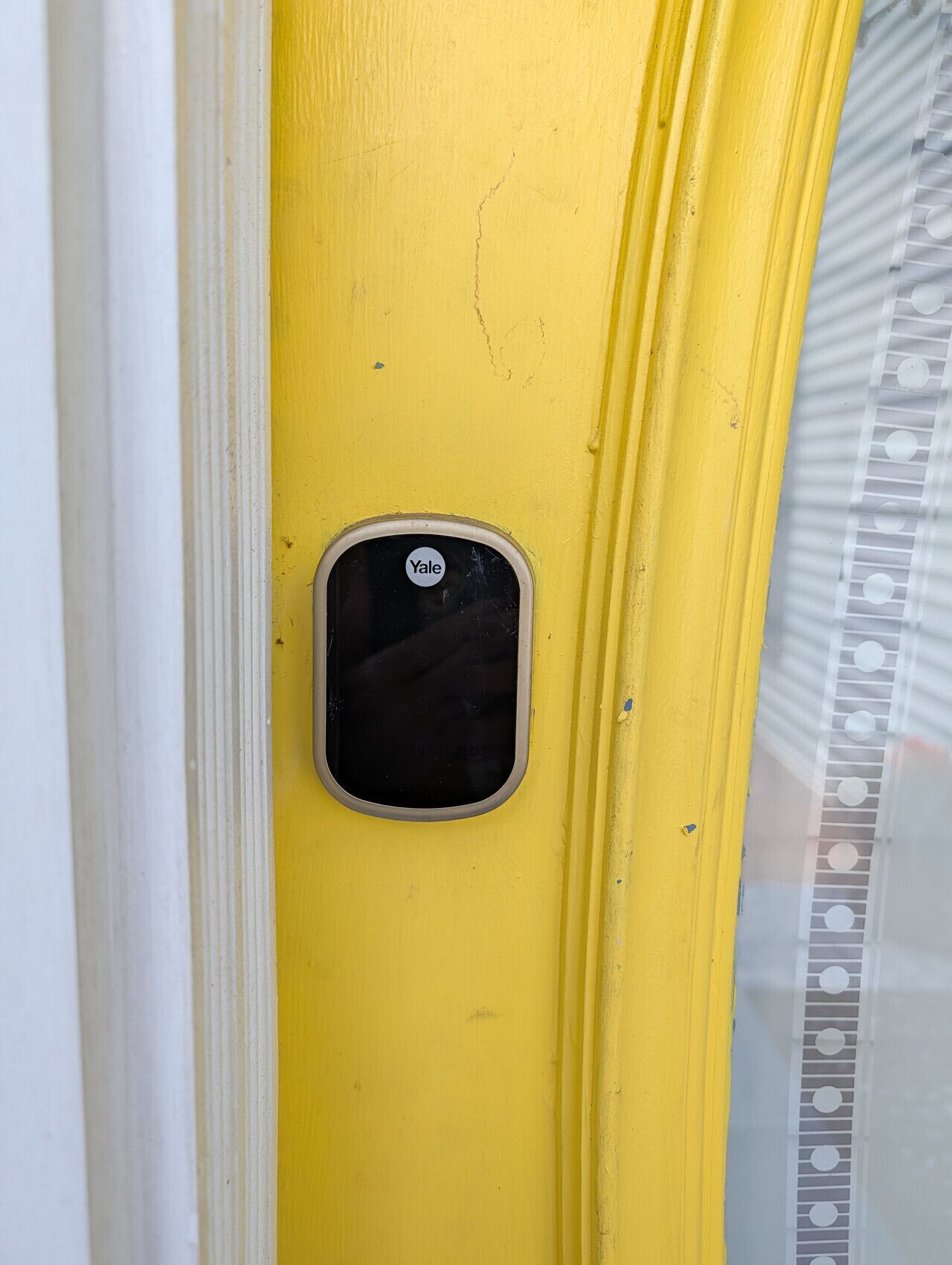 A yellow door with a Yale lock and a small window.