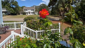 A residential property with a white fence, a red rose, and a house in the background. - Cozy, Cute, Private Ozark Suite 5 Mins to Hospital (Ozark)
